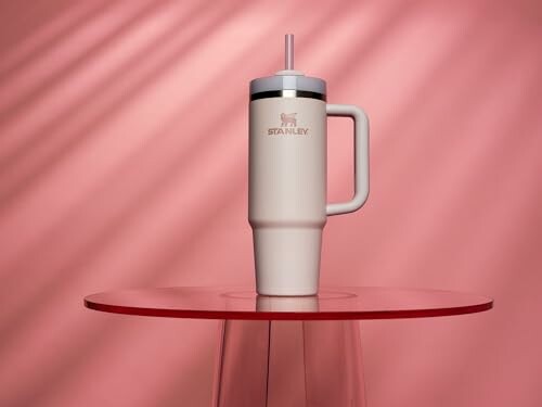 Stanley tumbler on a red table with pink background