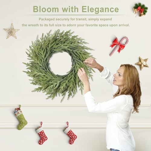 Woman decorating a wall with a Christmas wreath and festive ornaments.